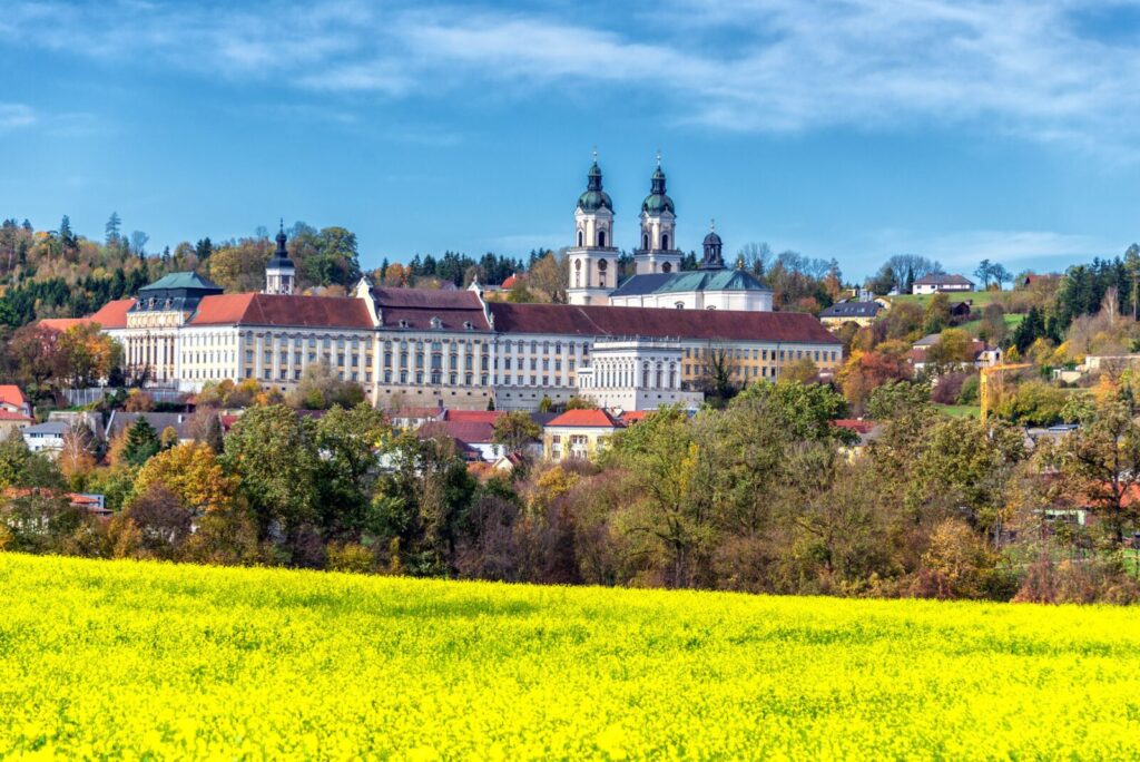 Blick auf St. Florian und Stiftskirche mit leuchtend gelbem Rapsfeld im Vordergrund